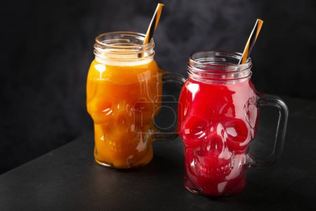 Halloween-Drink. Kürbisgetränk und Blutgetränk im Totenkopf-Glas.