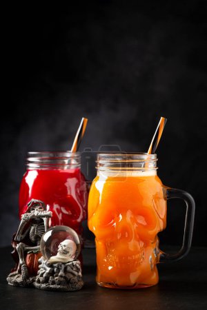 Halloween drink. Pumpkin drink and blood drink in skull glass. magic mug #709773386