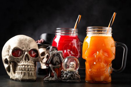 Halloween drink. Pumpkin drink and blood drink in skull glass.