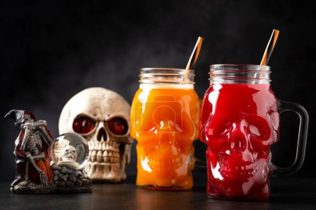 Bebida de Halloween. Bebida de calabaza y bebida de sangre en vaso de cráneo.