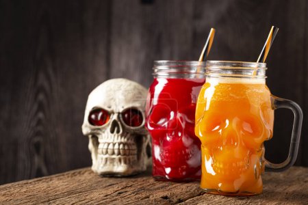 Bebida de Halloween. Bebida de calabaza y bebida de sangre en vaso de cráneo.