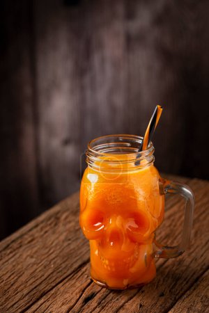 Halloween drink. Pumpkin drink in skull glass.
