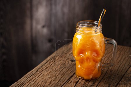 Halloween drink. Pumpkin drink in skull glass.