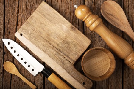 Cutting board with kitchen utensils on rustic background.