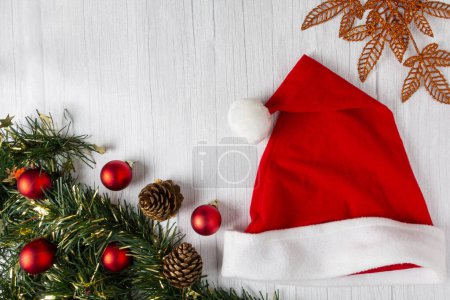 Foto de Sombrero de Papá Noel con decoraciones navideñas en mesa de madera. - Imagen libre de derechos