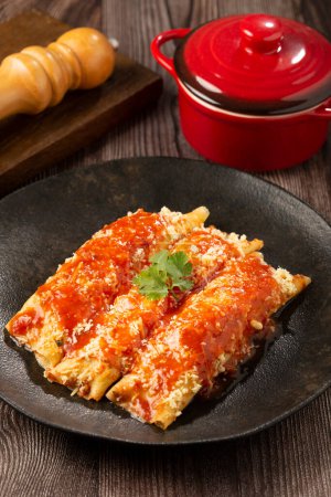 Téléchargez les photos : Crêpes farcies à la viande hachée et garnies de sauce tomate et fromage râpé. - en image libre de droit