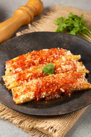 Foto de Panqueques rellenos de carne picada y cubiertos con salsa de tomate y queso rallado. - Imagen libre de derechos
