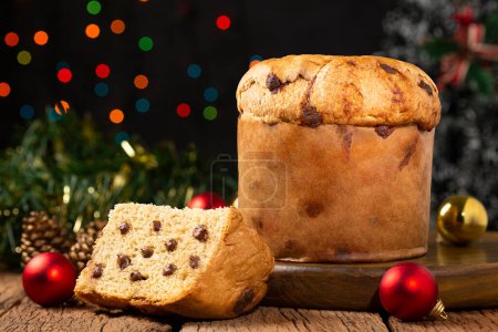 Foto de Delicioso panettone con chispas de chocolate en una mesa decorada para Navidad. - Imagen libre de derechos
