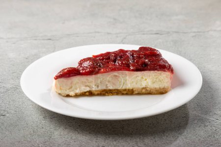 Foto de Tarta de queso glaseado de fresa sobre vajilla blanca sobre la mesa. - Imagen libre de derechos