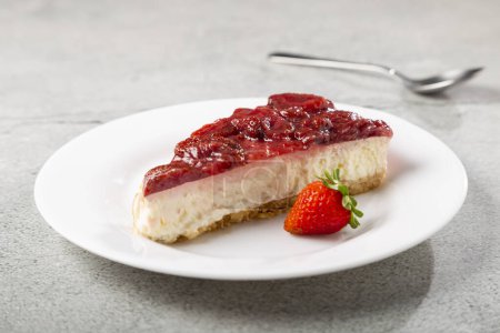 Foto de Tarta de queso glaseado de fresa sobre vajilla blanca sobre la mesa. - Imagen libre de derechos