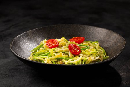 Photo for Zucchini spaghetti with tomatoes in garlic and oil. - Royalty Free Image