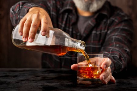 Mann füllt ein Glas mit Whiskey.