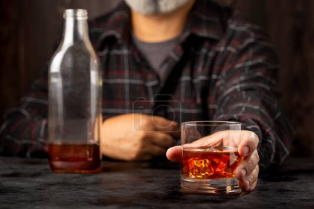 Mann hält Glas mit Whiskey in der Hand.