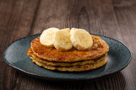 Banana and oat pancakes topped with sliced bananas and honey.