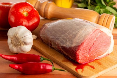 Téléchargez les photos : Pièce de viande crue avec des ingrédients sur la table. - en image libre de droit