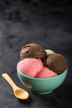 Foto de Cuenco con helado napolitano sobre fondo oscuro. - Imagen libre de derechos