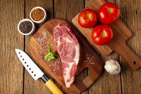 Foto de Carne ancha cruda lista para asar en una tabla de cortar de madera. - Imagen libre de derechos