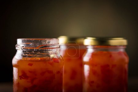 Pepper jelly in glass jar on the table.
