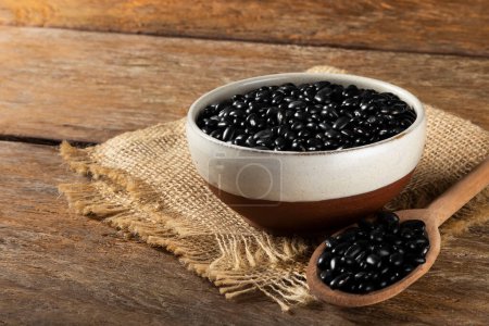 Photo for Black beans in wooden spoon and ceramic bowl. - Royalty Free Image