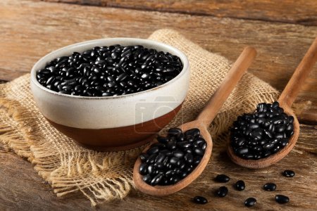 Photo for Black beans in wooden spoon and ceramic bowl. - Royalty Free Image