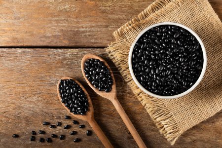 Foto de Frijoles negros en cuchara de madera y tazón de cerámica. - Imagen libre de derechos