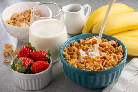 Téléchargez les photos : Flocons de maïs dans le bol avec des baies et du lait sur la table. - en image libre de droit