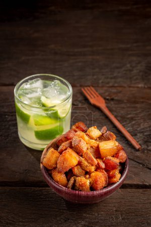 Photo for Pork rinds (torresmo) with caipirinha, typical Brazilian food. - Royalty Free Image