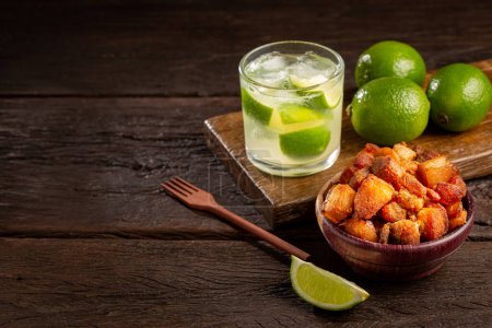 Photo for Pork rinds (torresmo) with caipirinha, typical Brazilian food. - Royalty Free Image