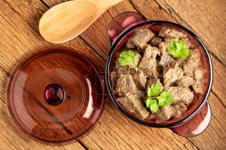 Téléchargez les photos : Cuire la viande dans la casserole sur la table en bois. Ragoût de viande. - en image libre de droit