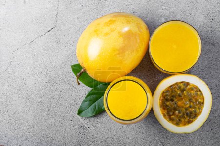 Photo for Glass with passion fruit juice and sliced passion fruit on the table - Royalty Free Image