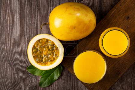 Photo for Glass with passion fruit juice and sliced passion fruit on the table - Royalty Free Image