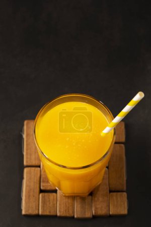 Zumo de mango en taza de vidrio sobre la mesa. Batido de mango.