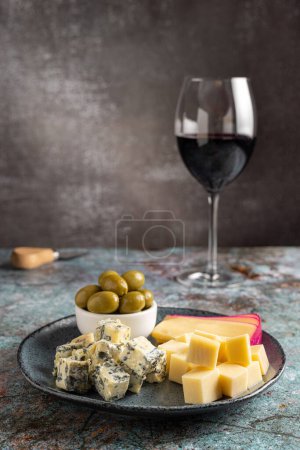 Teller mit verschiedenen Käsesorten und einem Glas Wein. Käsebrett.