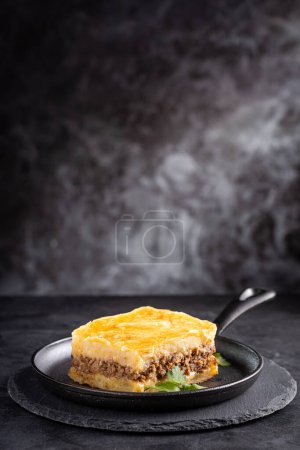 Téléchargez les photos : Morceau de tarte de berger sur une assiette sombre. - en image libre de droit