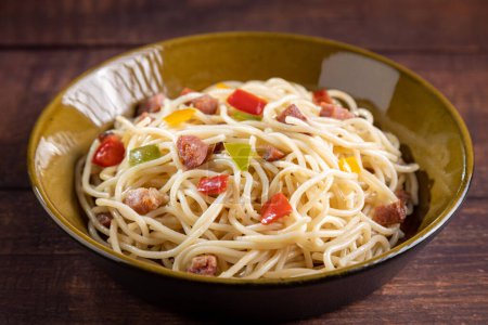 Teller mit Spaghetti, Speck und gehacktem Gemüse.