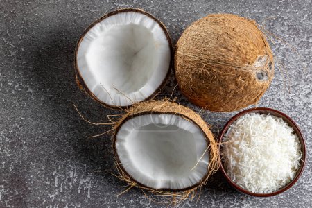 Téléchargez les photos : Noix de coco entière, morceaux de noix de coco et noix de coco râpée sur la table. - en image libre de droit