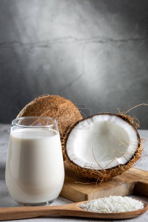 Foto de Vaso de leche de coco con trozos de coco sobre la mesa. - Imagen libre de derechos