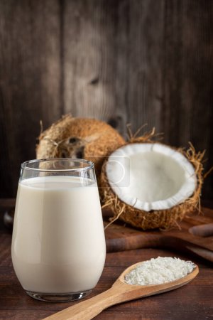 Photo for Glass of coconut milk with pieces of coconut on the table. - Royalty Free Image