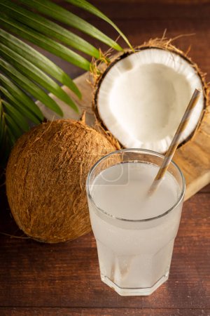 Photo for Glass with fresh coconut water and coconuts on the table. - Royalty Free Image