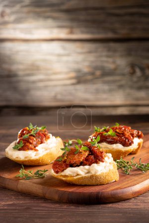 Photo for Bruschetta with sun-dried tomatoes, cream cheese and greens. - Royalty Free Image