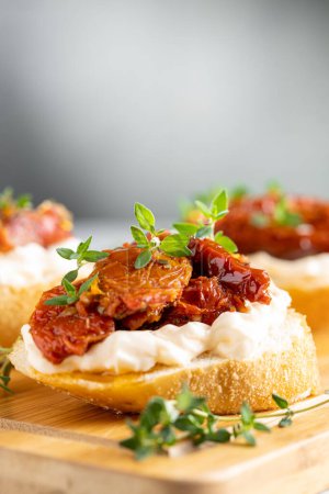 Photo for Bruschetta with sun-dried tomatoes, cream cheese and greens. - Royalty Free Image