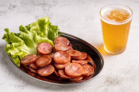 Téléchargez les photos : Saucisse de pepperoni frite tranchée avec verre de bière sur la table - en image libre de droit