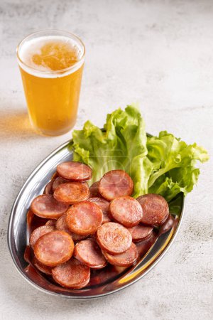 Photo for Sliced fried pepperoni sausage with glass of beer on the table - Royalty Free Image