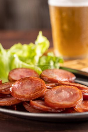 Photo for Sliced fried pepperoni sausage with glass of beer on the table - Royalty Free Image