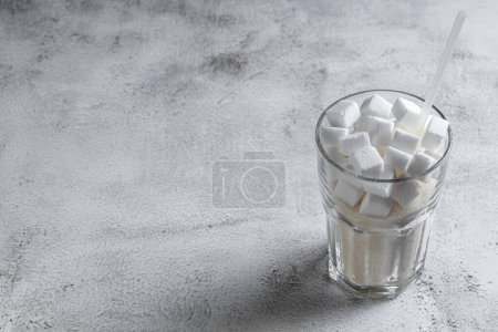 Photo for White sugar cubes in transparent glass cup. - Royalty Free Image
