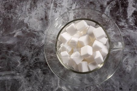 Photo for White sugar cubes in transparent glass cup. - Royalty Free Image