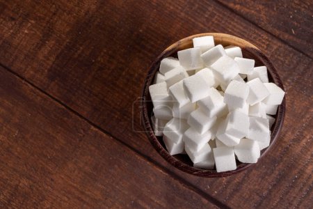 White sugar cubes in wooden bowl.