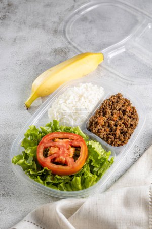Lunchbox with lettuce salad with tomato, rice and ground beef.