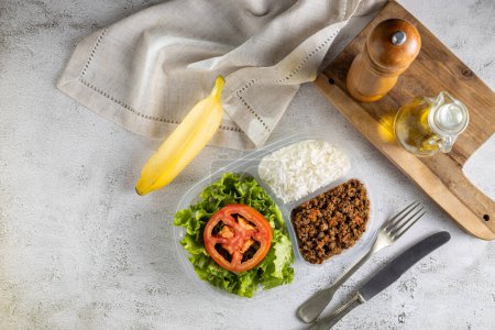 Lunchbox with lettuce salad with tomato, rice and ground beef.