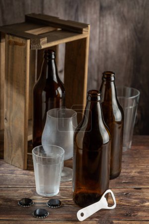 Téléchargez les photos : Bouteilles de bière ambre vides sur fond bois rustique. - en image libre de droit